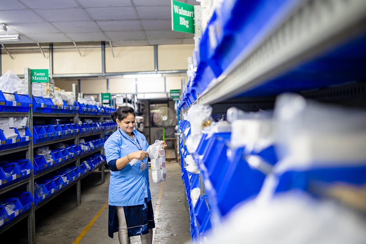 why-choose-us Female worker organizes shelves in a warehouse. Industrial setting with labeled storage bins.