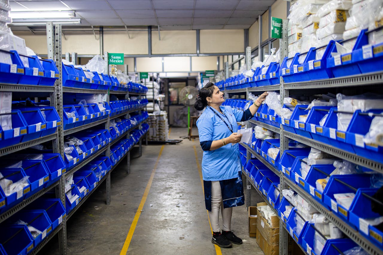 our-story A worker in a warehouse organizing inventory on shelves with blue bins.
